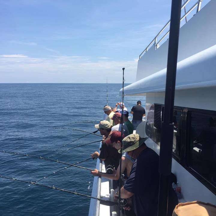 A group fishing on the side of a boat