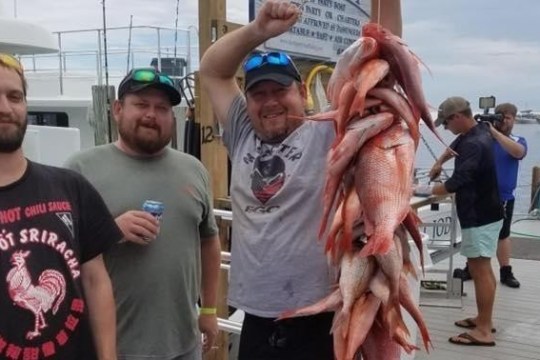Artūrs Štālbergs et al. standing next to a person holding a fish
